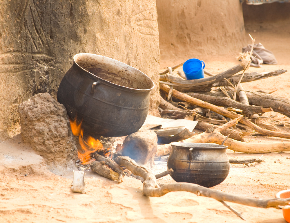 Een kleurrijke verzameling van essentiële Afrikaanse keukentools, waaronder een Potjie pot, een Tajine, een kalebas en een houten vijzel met stamper, uitgestald op een rustieke houten tafel.